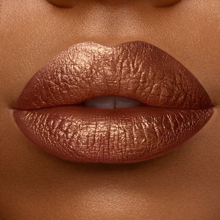 Labios con labial metálico cobrizo sobre piel morena, maquillaje brillante y elegante para tonos de piel oscuros.