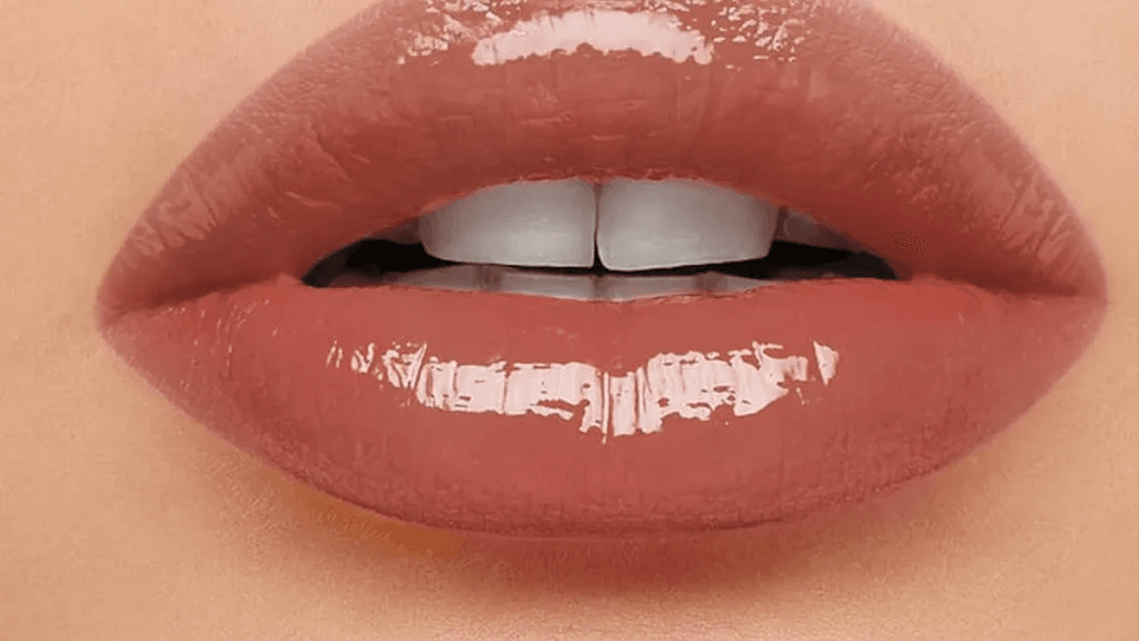 Labios maquillados con gloss nude brillante, acabado luminoso para un maquillaje natural y voluminoso.