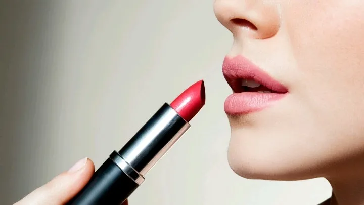 Aplicación de labial rojo en labios femeninos, maquillaje clásico para resaltar la belleza natural.