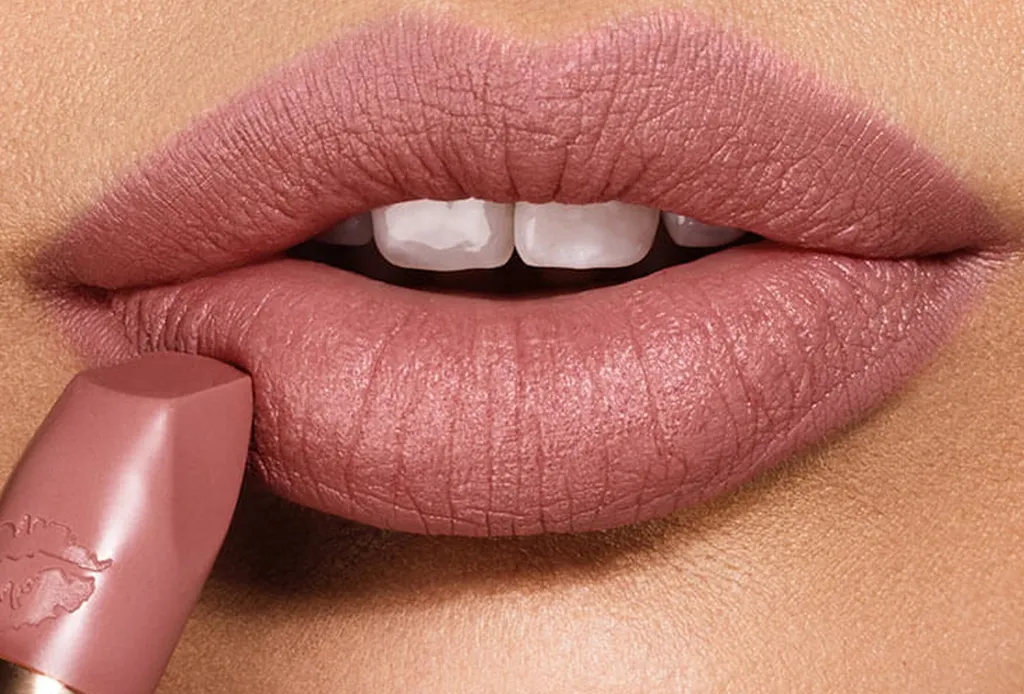 Mujer aplicando labial nude mate, resaltando unos labios suaves y naturales con un acabado elegante.