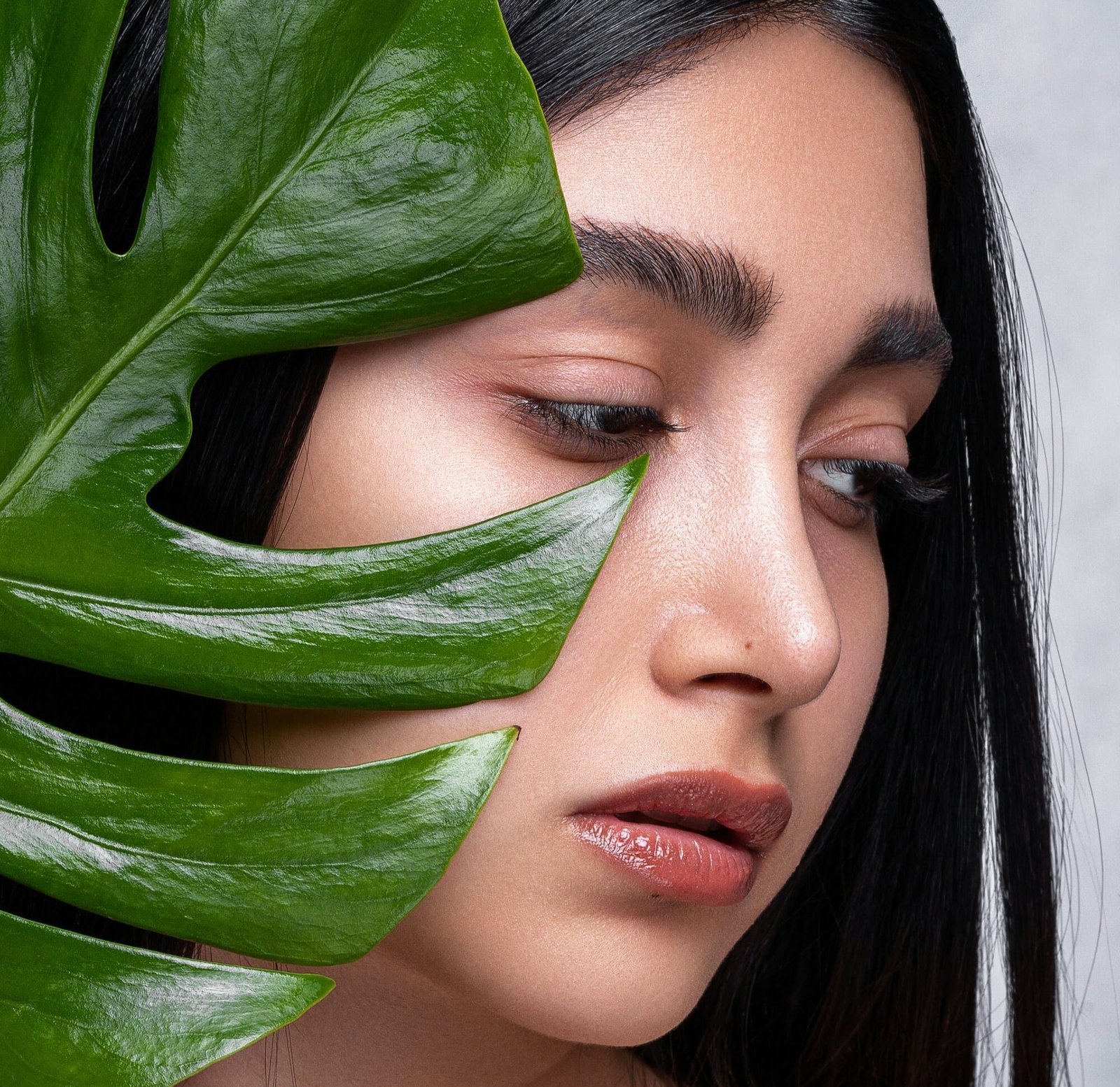 Una mujer con piel radiante y cejas gruesas, belleza natural. Fotografía de belleza con enfoque en skincare, maquillaje minimalista y conexión con lo orgánico. Cosmética natural y tendencias en maquillaje natural y estética eco-friendly.