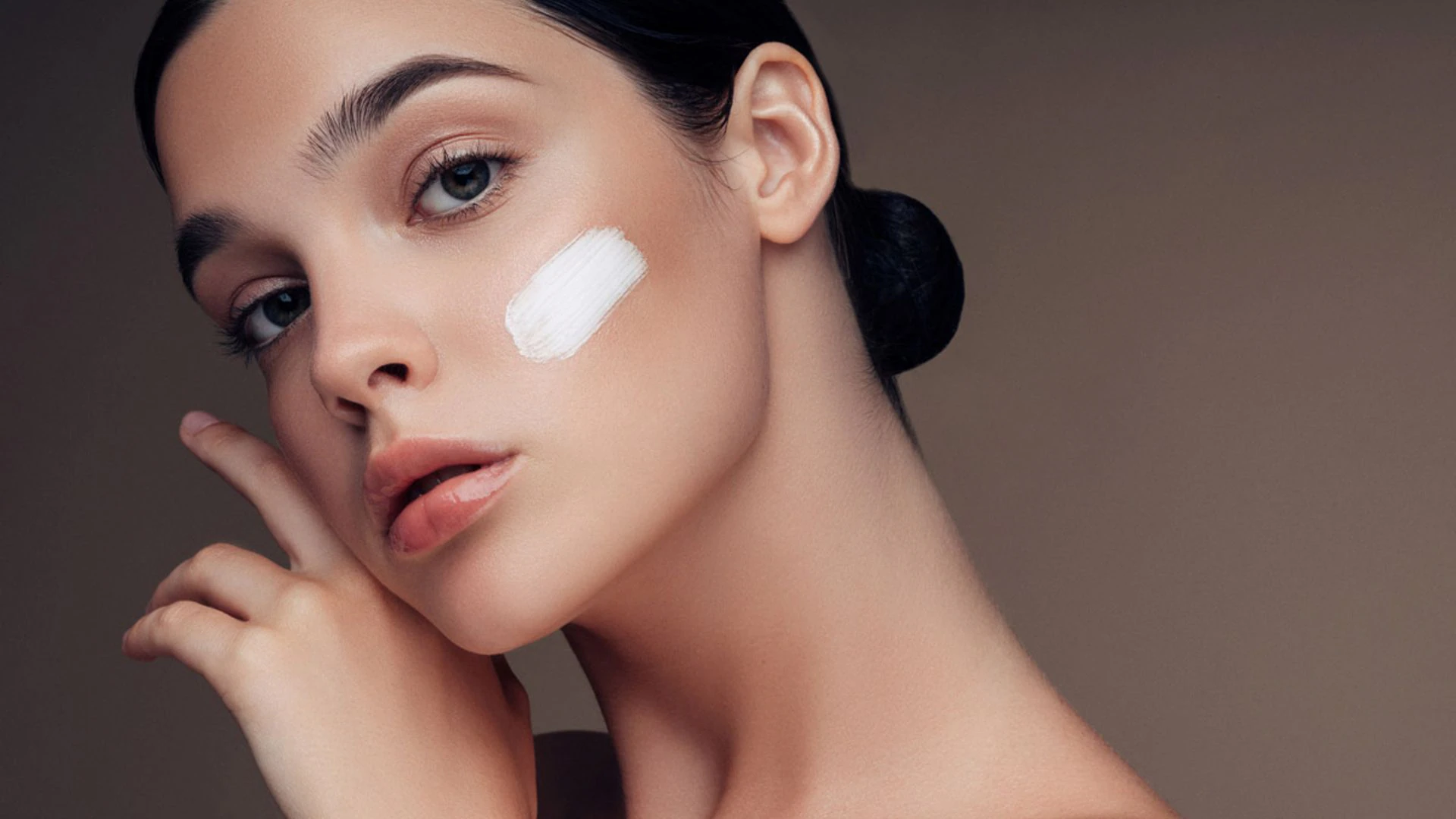 mujer posando con crema en la cara para fotografía