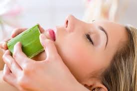 Mujer disfrutando de un tratamiento facial con aloe vera, rodeada de un ambiente tranquilo y productos de belleza naturales.