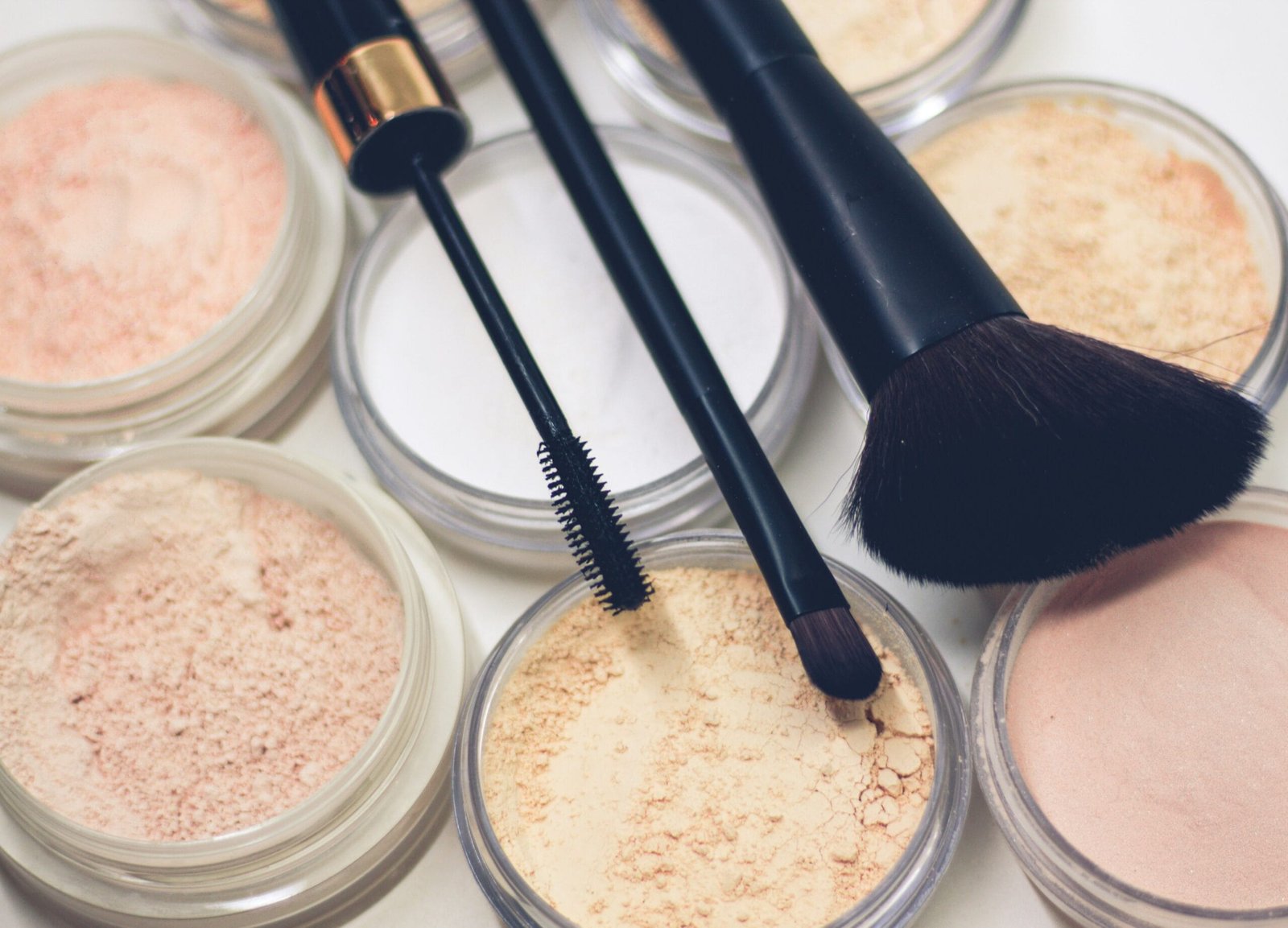 Maquillaje en polvo suelto y brochas profesionales. Polvos translúcidos y compactos en tonos neutros y beige, ideales para sellar el maquillaje y matificar la piel. Cepillo de rímel y brochas de maquillaje de alta calidad con mango negro y cerdas suaves. Cosméticos para un acabado profesional, perfectos para el contouring y la fijación del maquillaje. Belleza, maquillaje profesional y productos para el cuidado de la piel.